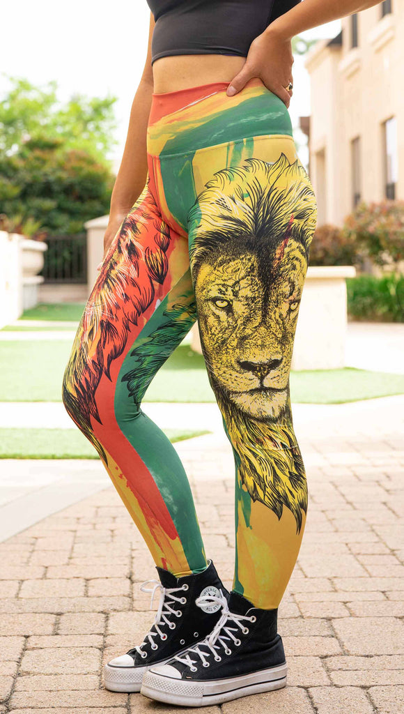 Model wearing WERKSHOP Lion of Zion Athleisure Leggings. The leggings feature a hand illustration of a lion over organic brustrokes in Rastafarian colors.