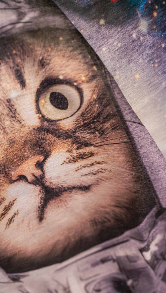 Decorative Chenille Tapestry printed with limited edition artwork by our Female Founder, Chriztina Marie. The artwork features an adorable domestic house cat wearing an astronaut uniform, floating in outer space with a nebula behind him. This is a zoomed in image of his face that shows the soft texture of the fabric.
