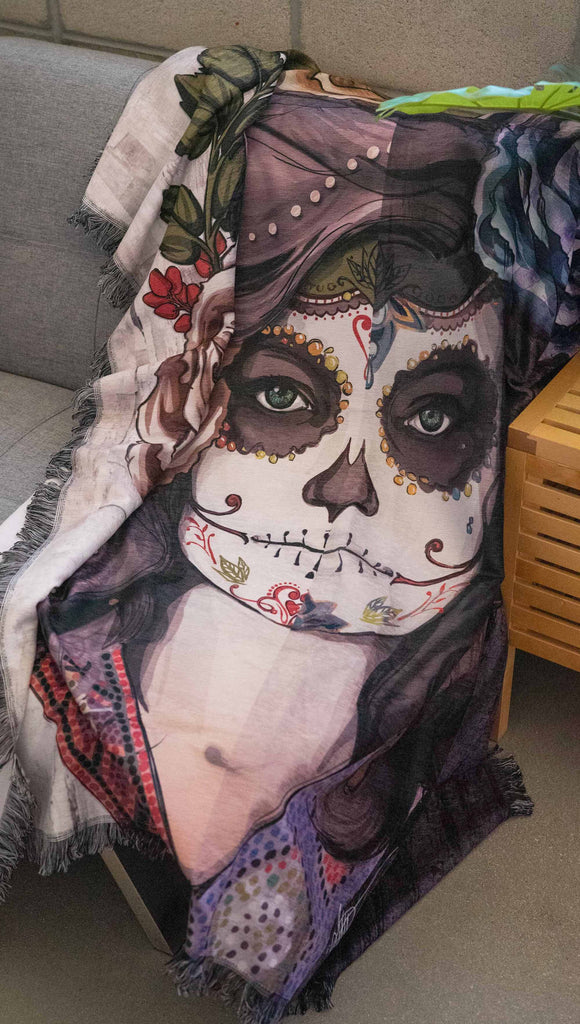 Decorative Chenille Tapestry printed with limited edition artwork by our Female Founder, Chriztina Marie. The artwork celebrates Dia De Los Muertos with a drawing of a girl wearing sugarskull makeup surrounded by a wreath of roses.