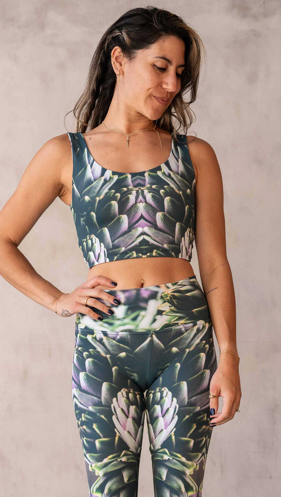 irl wearing the WERKSHOP Reversible Artichoke and Rosaline Top. This image shows the Artichoke side. It has pops of bright green and bright purple over a mostly dark green base. It is a very geometric and fractal design.