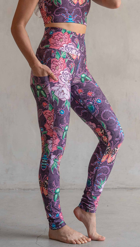 Side view of model wearing WERKSHOP Enchanted Garden EnviSoft Leggings with Pockets. The fabric is printed with original artwork by our Female Founder, Chriztina Marie. The artwork printed not the fabric features Butterflies, Beetles and Peonies over a warm fuchsia with bright bold pops of color on each beetle and Butterfly.