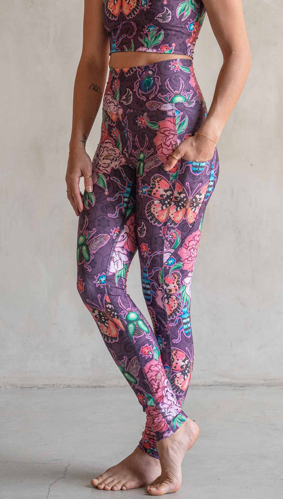 Side view of model wearing WERKSHOP Enchanted Garden EnviSoft Leggings with Pockets. The fabric is printed with original artwork by our Female Founder, Chriztina Marie. The artwork printed not the fabric features Butterflies, Beetles and Peonies over a warm fuchsia with bright bold pops of color on each beetle and Butterfly.