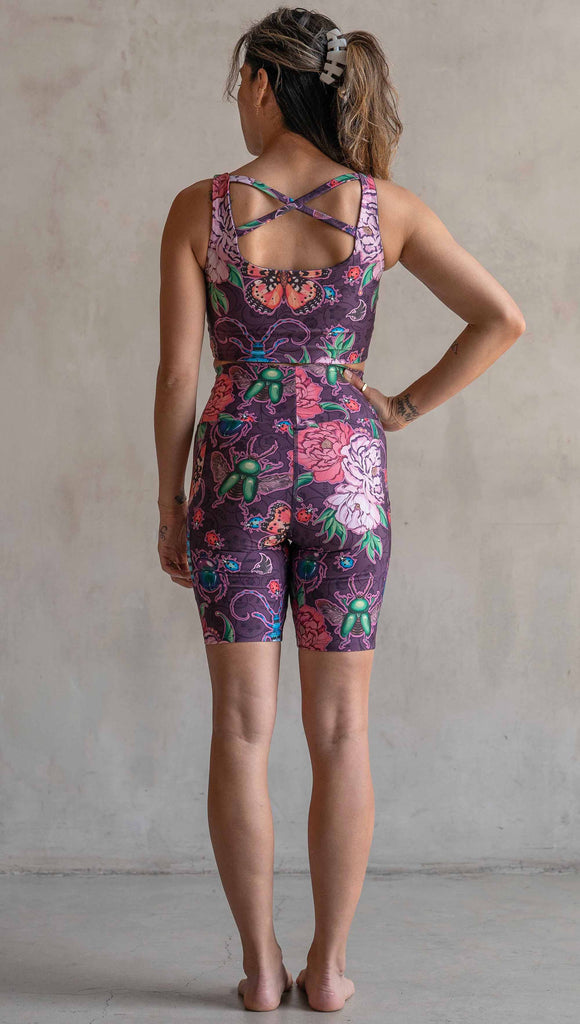 Back view of model wearing WERKSHOP Enchanted Garden EnviSoft Bicycle length shorts with pockets. The fabric is printed with original artwork by our Female Founder, Chriztina Marie. The artwork printed not the fabric features Butterflies, Beetles and Peonies over a warm fuchsia with bright bold pops of color on each beetle and Butterfly.