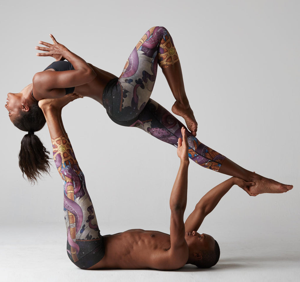 Yogis (Koya Webb and Andrew Sealy) doing Acro Yoga while both wearing WERKSHOP Octopus Capri Leggings