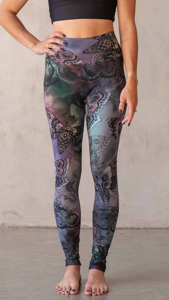 Front view of model wearing WERKSHOP Moths athlisure leggings. The artwork on the leggings is of hand drawn moths with muted pops of mauve and peach over an edgy "oil slick" inspired watercolor background.