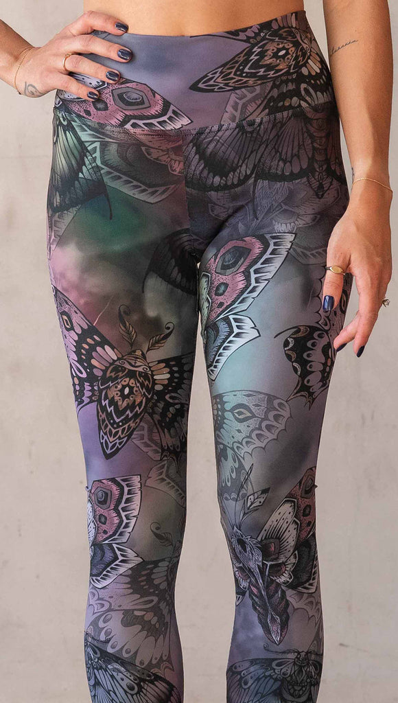 Zoomed in view of model wearing WERKSHOP Moths athlisure leggings. The artwork on the leggings is of hand drawn moths with muted pops of mauve and peach over an edgy "oil slick" inspired watercolor background.