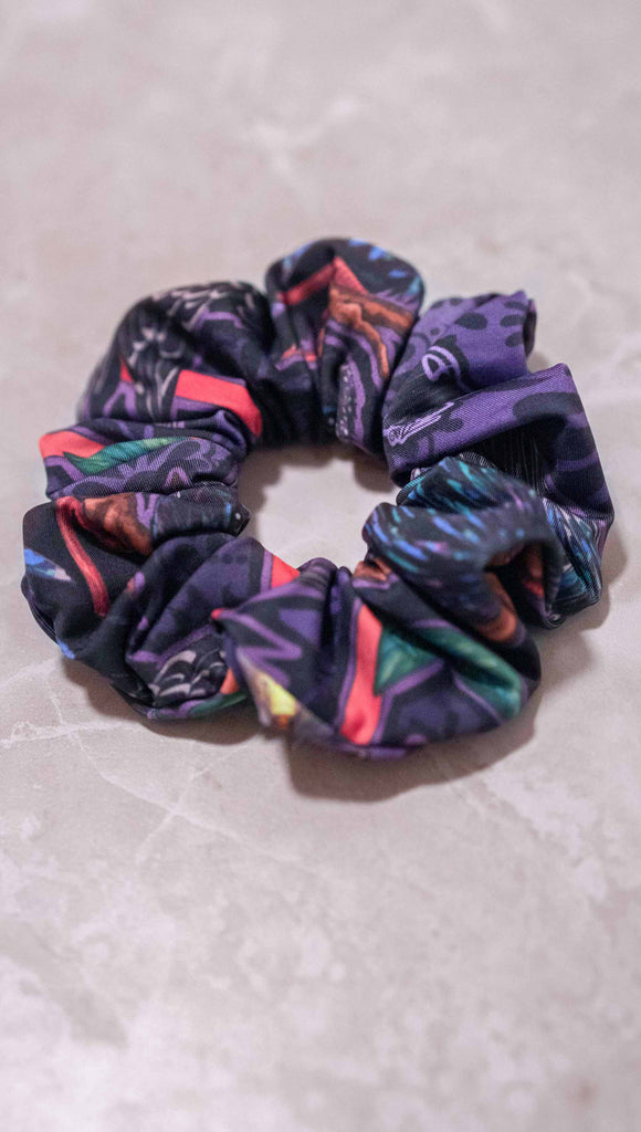 WERKSHOP Starlings hair scrunchie. The scrunchie is mostly a deep purple/blue with little bright pops of coral and green.