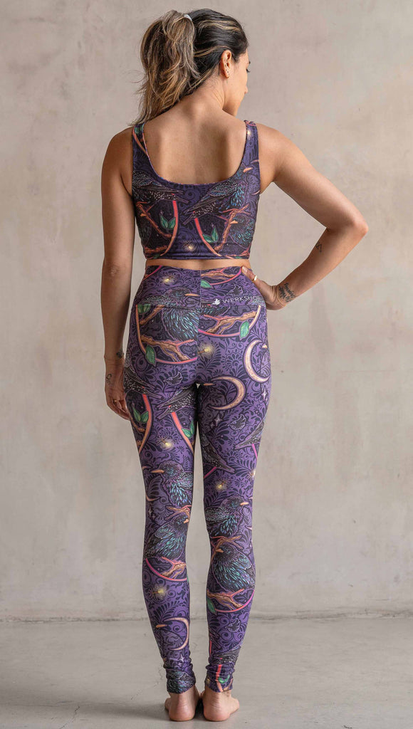 Back view of model wearing WERKSHOP Starlings Athleisure Leggings. The fabric is printed with original artwork by our Female Founder, Chriztina Marie. Featuring European Starlings perched on a branch near a crescent moon and fireflies. The colors are warm purples with pops of pink, gold and green.