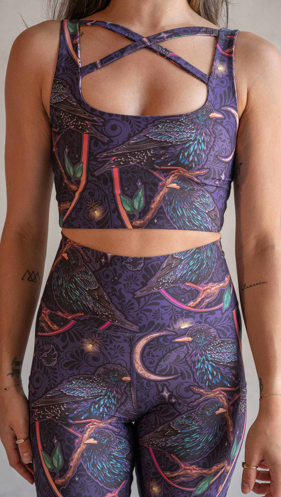 Front view of model wearing WERKSHOP Starlings and Enchanted Garden 4-Way reversible top. The fabric is printed with original artwork by Chriztina Marie. One side features European Starlings perched on a branch near a crescent moon and fireflies. The colors are warm purples with pops of pink, gold and green. The other side features Butterflies, Beetles and Peonies over a warm fuchsia with bright bold pops of color on each beetle and Butterly.