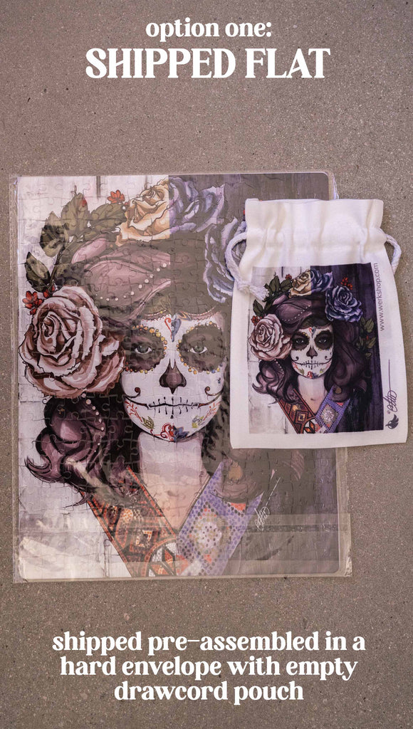 WERKSHOP Sugar Skull Mashup Puzzle. The artwork celebrates Dia De Los Muertos with a drawing of a girl wearing sugarskull makeup surrounded by a wreath of roses. Option 1: Shipped pre-assembled in a hard envelope with empty drawcord pouch.