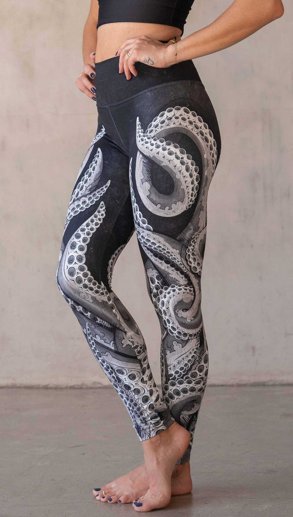 Model wearing WERKSHOP Tentacles Athleisure Leggings. The artwork on the leggings features hand drawn tentacles wrapping up and around each leg in colors of black and white with distressed texture.