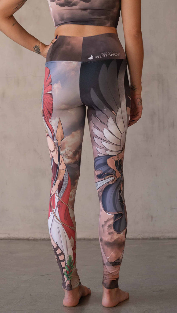 Model wearing WERKSHOP Valkyrie + Athena Mashup leggings. The leggings are printed with original artwork by Chriztina Marie. One leg features Athena, the goddess of war standing on a cliff’s edge. She is holding a spear with one hand and her owl with the other. The opposite leg features a Valkyrie warrior from Norse Mythology flying through a dark sky holding a shield and swords. Her hair is in braids and she is wearing armor and a viking helmet.