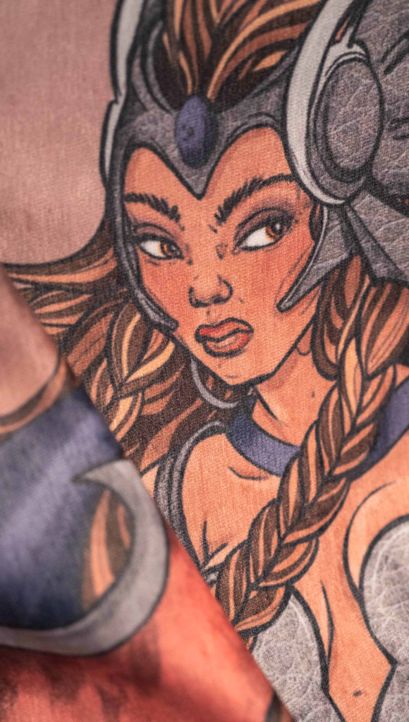 Decorative Chenille Tapestry printed with limited edition artwork by our Female Founder, Chriztina Marie. The artwork features a valyrkie warrior flying through a stormy sky holding a sword and shield. The colours are rich and warm with peach/orange tones and some pops of blue. This image is zoomed in on the face of the valkyrie showing the soft texture of the fabric.