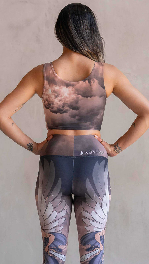 Side view of model wearing WERKSHOP Athena and Valkyrie reversible top. This top is two way reversible and each side matches either our Athena or Valkyrie leggings. The Athena side of the top features a cloudy blue sky with rays of sunlight. The Valkyrie side features an ominous taupe and warm gray stormy sky with lightening bolts