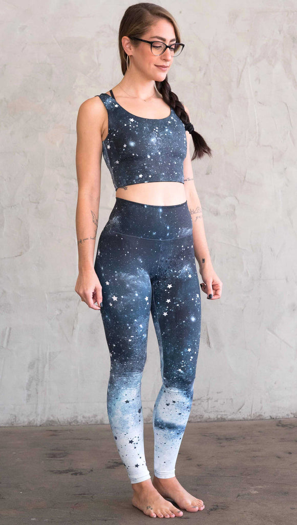 right-side view of a girl wearing our moon phases athleisure leggings - with the phases of the moon printed on the wearer's left leg on a starry night sky with all zodiac constellations in the background
