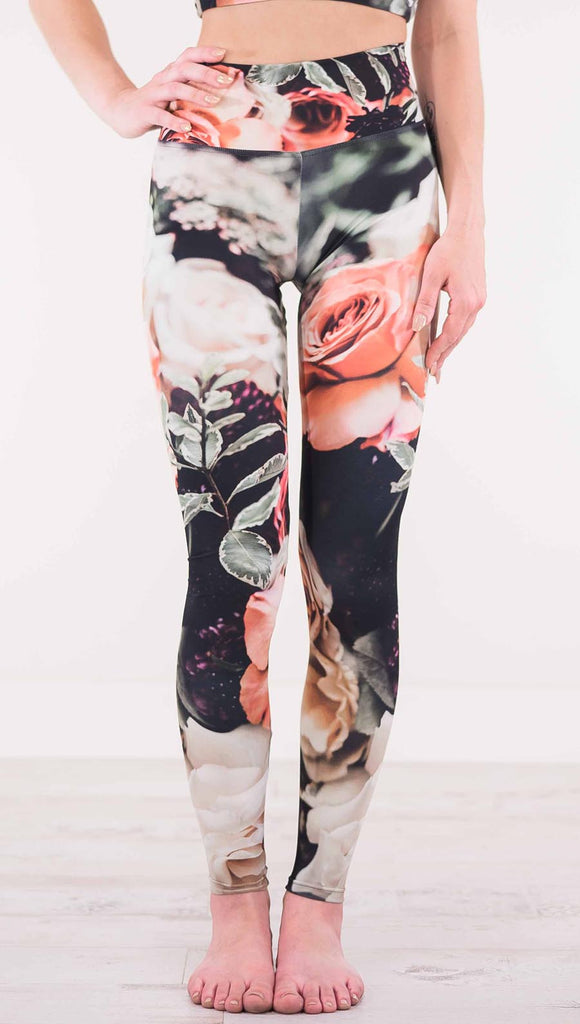 Front view of model wearing black athleisure leggings with pink and white roses and leafy greens throughout