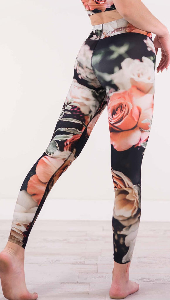 Back view of model wearing black triathlon leggings with pink and white roses and leafy greens throughout