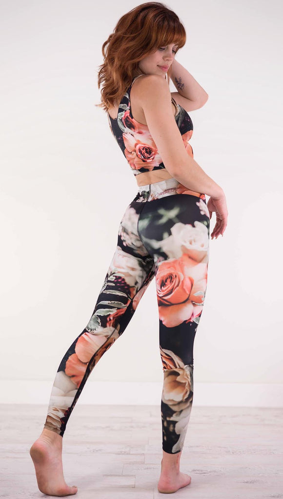 Back view of model wearing black triathlon leggings with pink and white roses and leafy greens throughout