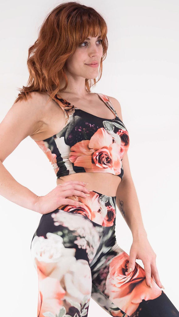 Right view of model wearing the Bodacious Bouquet reversible crop top. It is in a black color with pink and white roses and leafy greens throughout