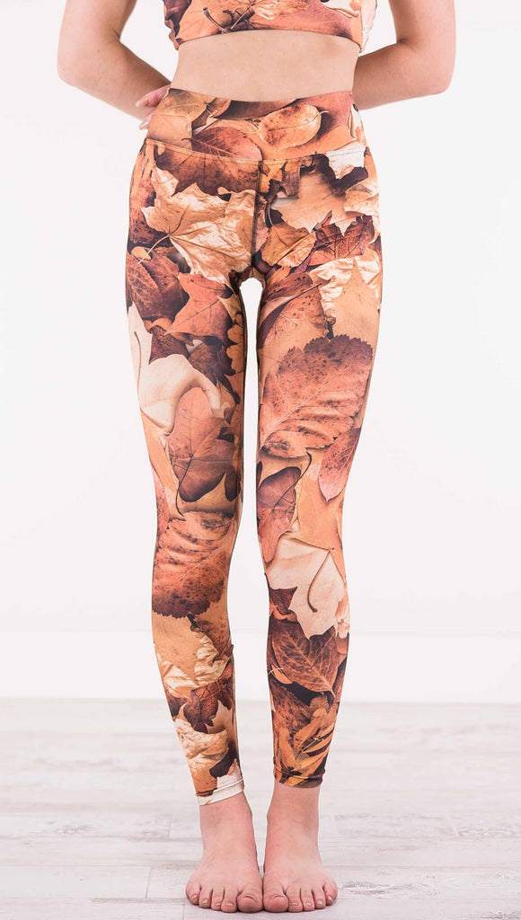 Front view of model wearing triathlon leggings that have different shades of orange autumn leaves