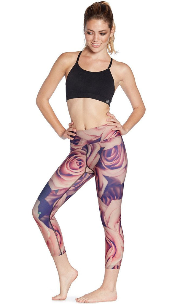 front view of model wearing printed capri leggings with all-over rose design motif and sports top
