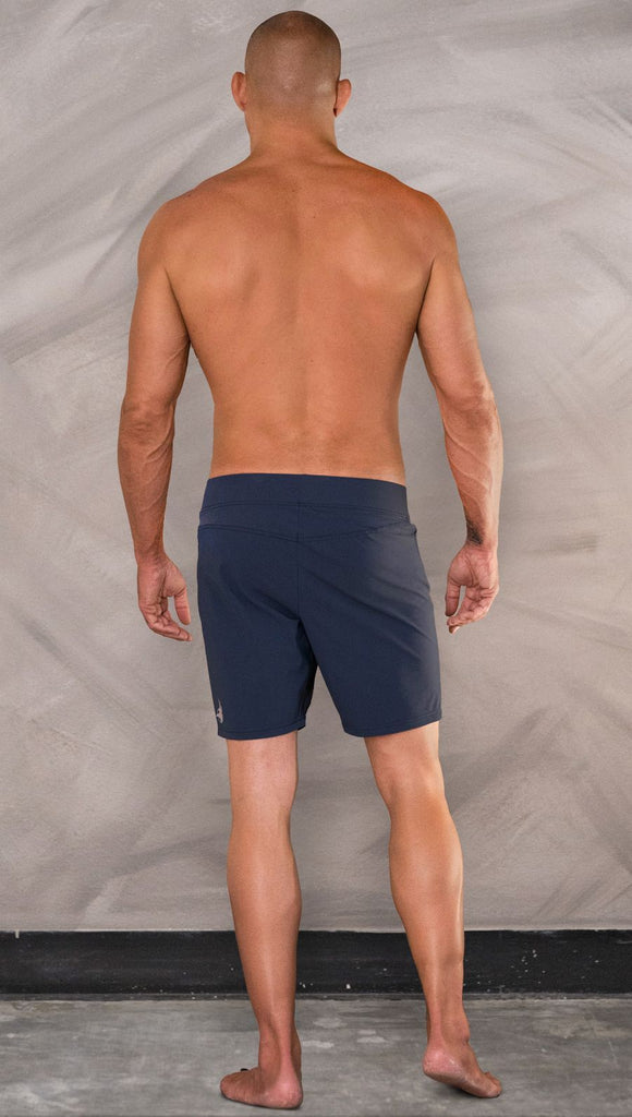 Back view of model wearing men's blue performance shorts with slim fit.