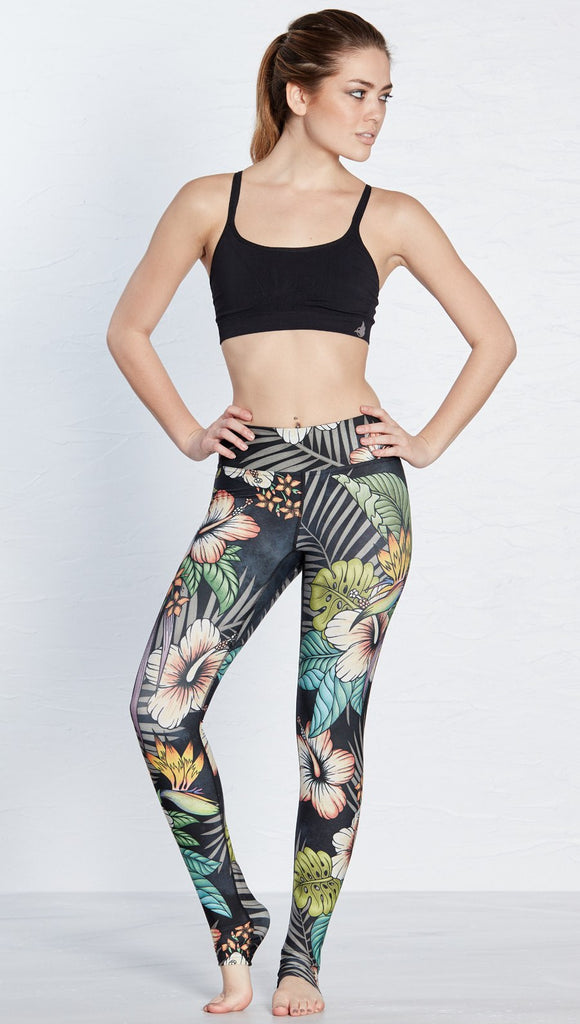 front view of model wearing printed full length leggings with tropical floral design and black background