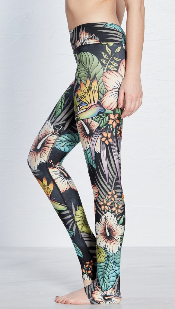 close up left side view of model wearing printed full length leggings with tropical floral design and black background