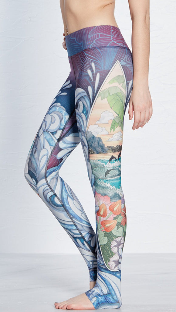 close up left side view of model wearing island surfboard and waves themed printed full length leggings