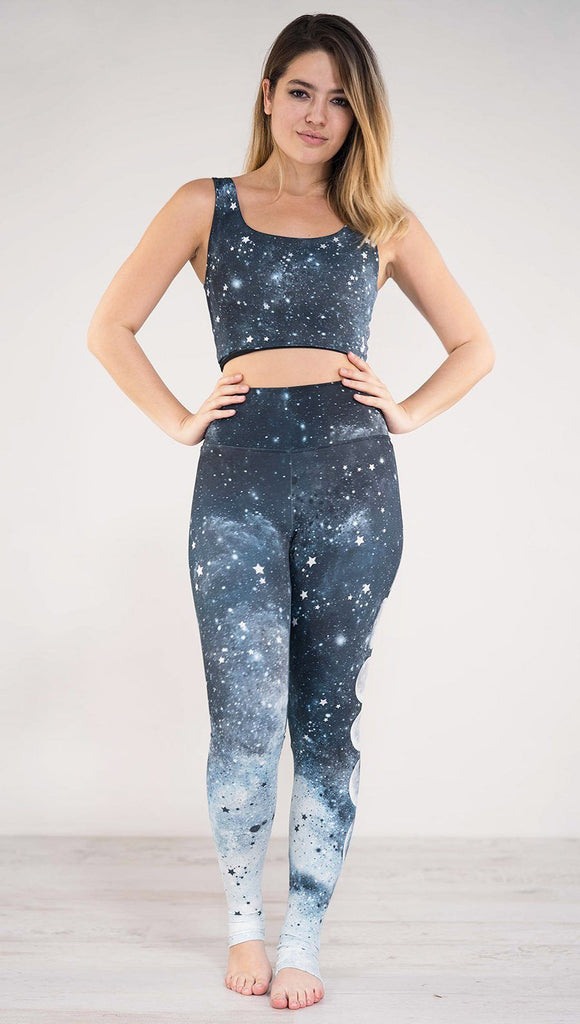 Front side view of model wearing blue full length athleisure leggings that fade to white at the bottom with tiny white stars across the leggings