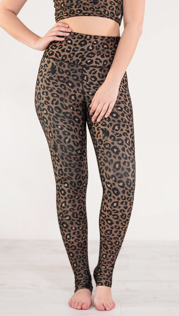 Front view of model wearing reversible tan leopard print athleisure leggings in the colors tan and black