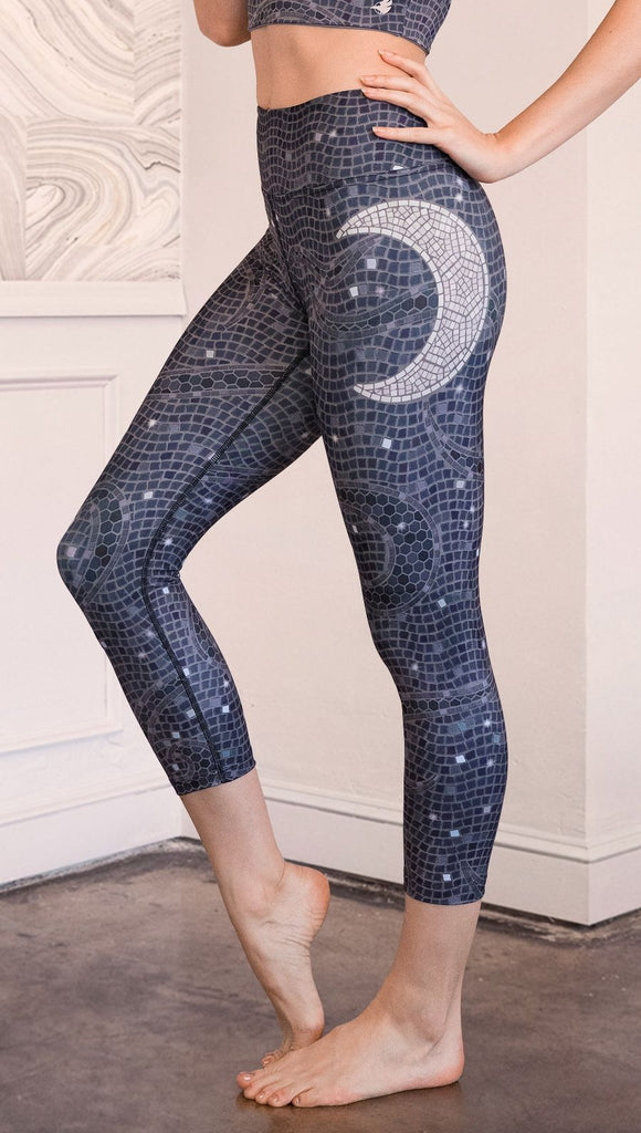Close up left side view of model wearing mosaic printed capri leggings with moon artwork on left hip