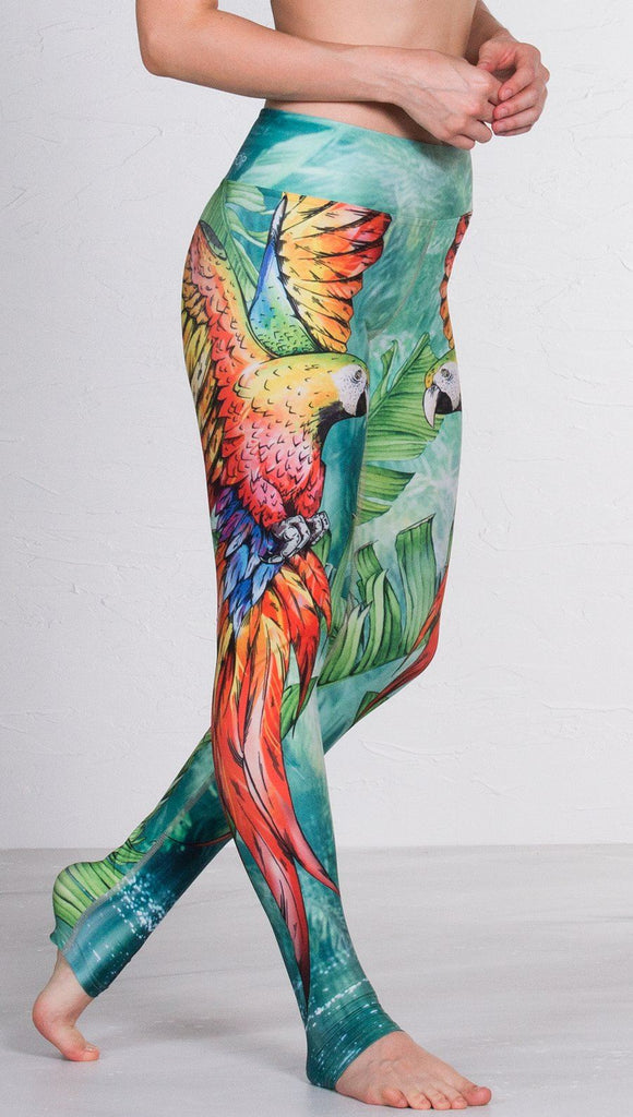 closeup right side view of model wearing macaw themed full length leggings