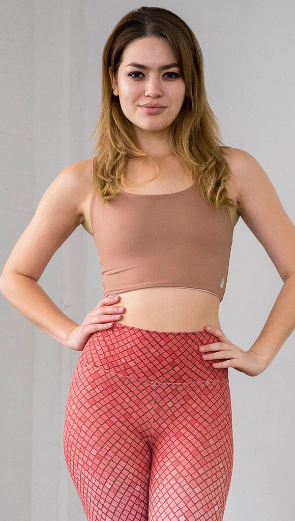 Three quarter length front view of model wearing a reversible light brown/medium skin tone crop top with a beige/lighter skin top on the inside