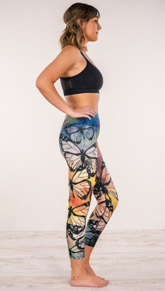 Right side view of model wearing rainbow butterfly themed printed capri leggings