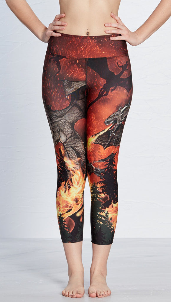 closeup front view of model wearing fire breathing dragon themed printed capri leggings