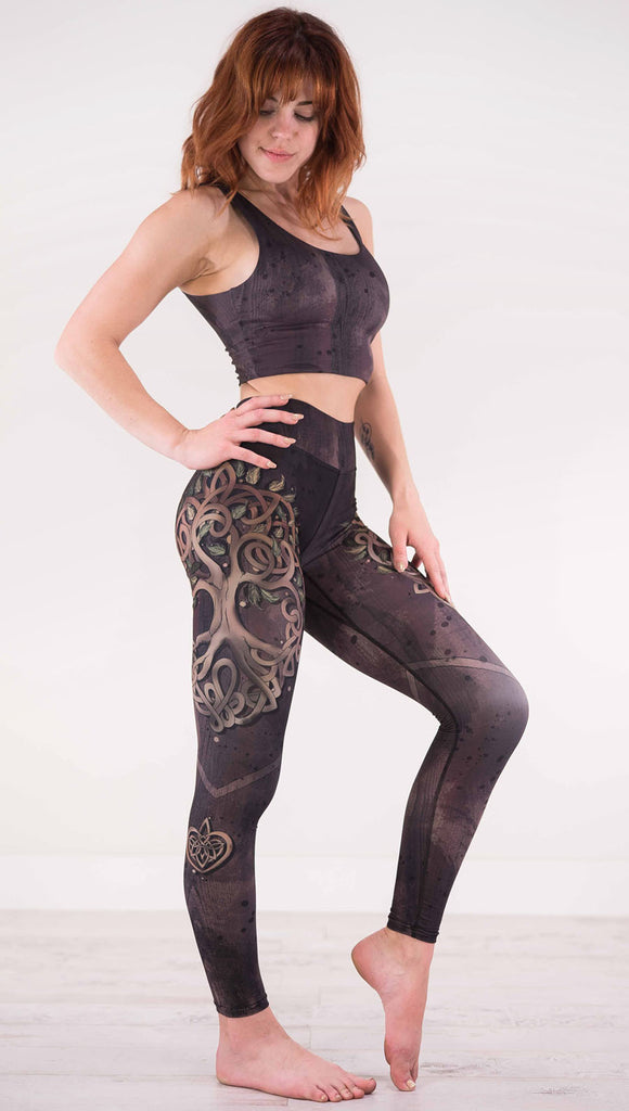 Right view of model wearing the Tree of Life triathlon leggings in a brown wood grain print with a tree on the side