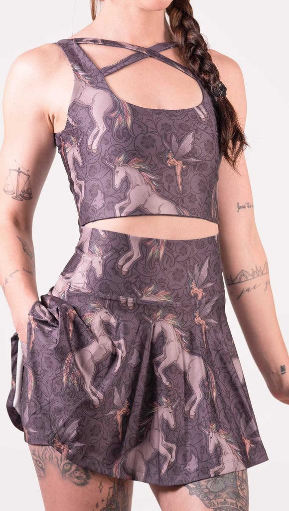 Zoomed in photo of model wearing WERKSHOP featherlight skirt with Original Unicorn artwork. The unicorns have soft rainbow colored hair and a small pixie friend over a purple background. The skirt has built in shorts with a pocket on each hip big enough to hold a phone