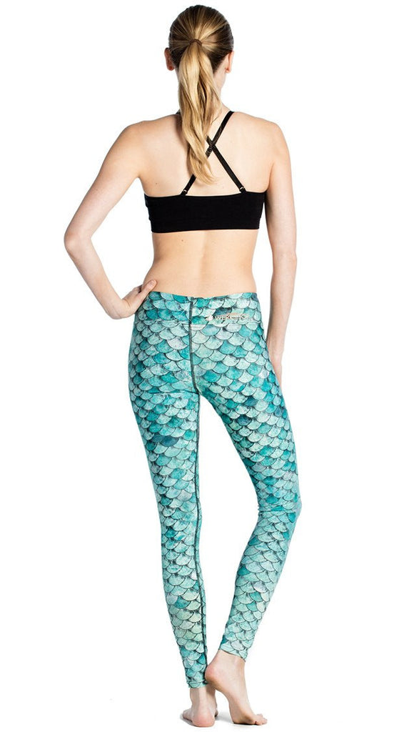 back view of model wearing teal mermaid / fish scale printed full length leggings