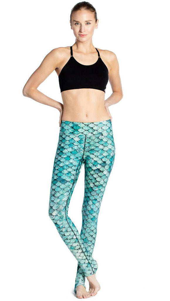 front view of model wearing teal mermaid / fish scale printed full length leggings