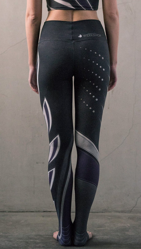 Rear view of model wearing black printed full-length leggings with purple and gray stripe design