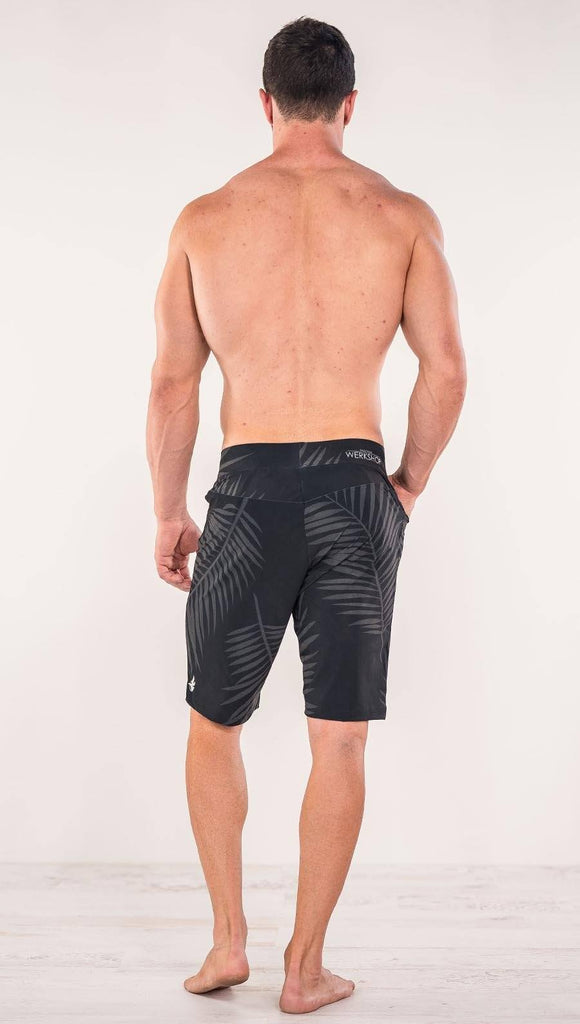 Back view of model wearing tropical palm fronds printed men's performance shorts