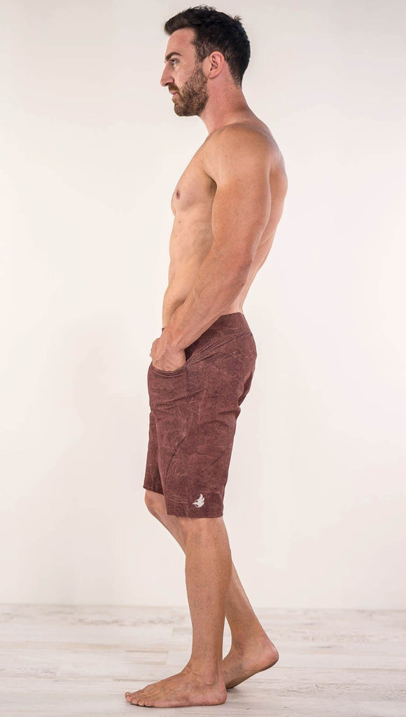 Left view of model wearing brick red printed men's performance shorts