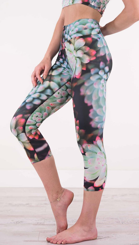 Left view of model wearing black capri leggings with green succulent plants with pink tips throughout