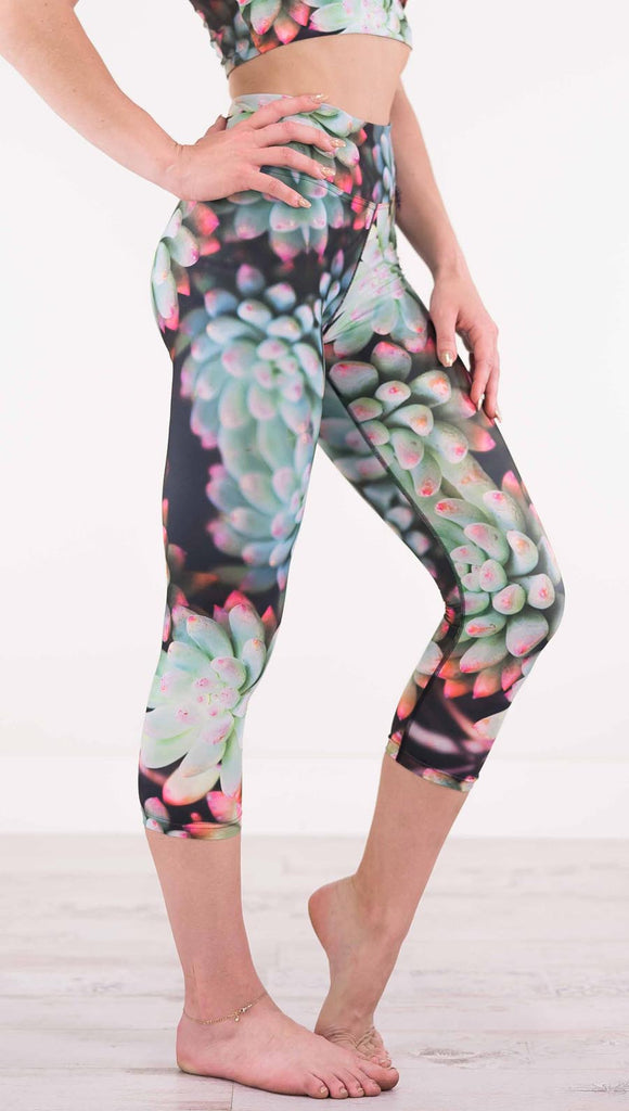 Right view of model wearing black capri leggings with green succulent plants with pink tips throughout