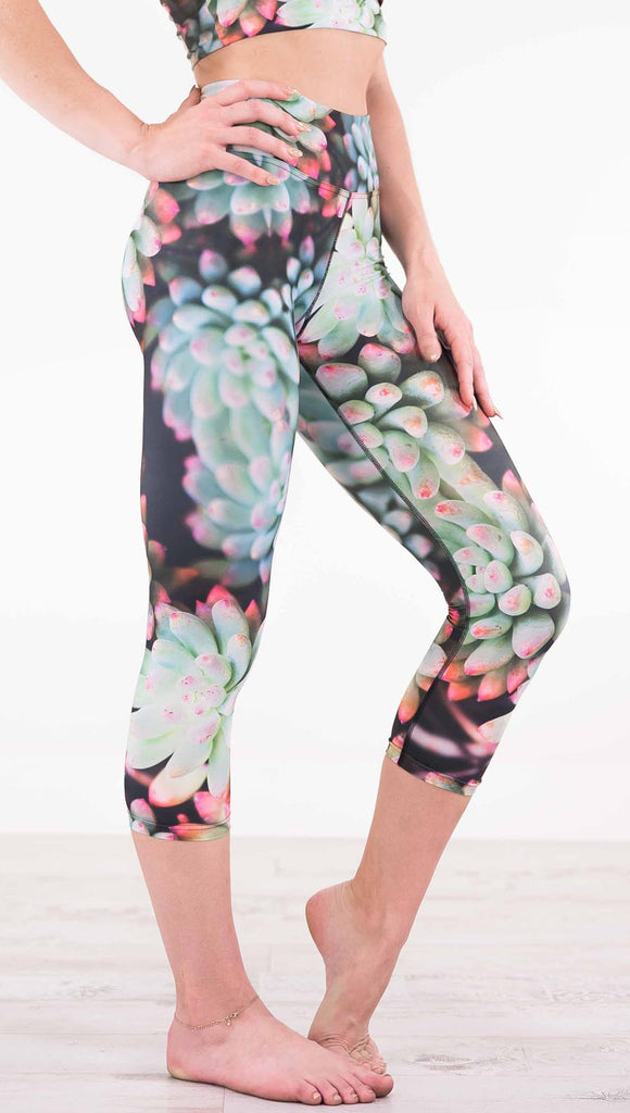 Right view of model wearing black capri leggings with green succulent plants with pink tips throughout