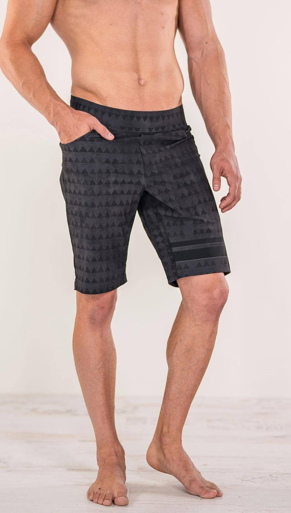 Close up front view of model wearing charcoal black printed performance shorts with slim fit and distressed tribal inspired art