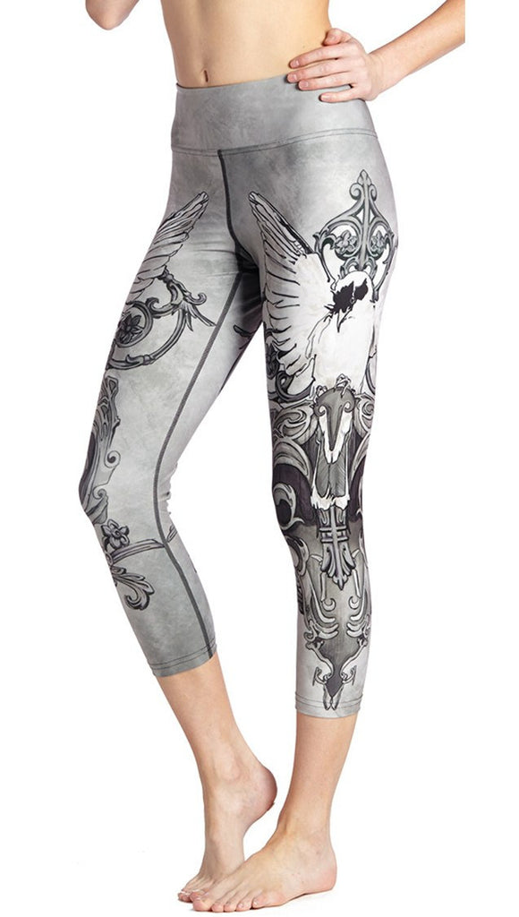 close up side view of model wearing black and white fantasy dove themed printed capri leggings