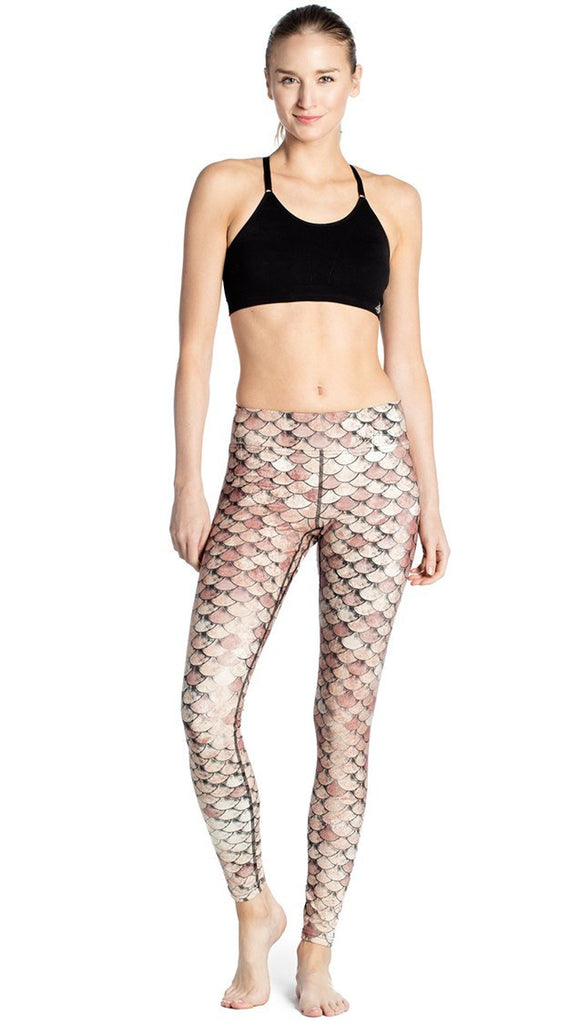 front view of model wearing gold mermaid scale themed printed full length leggings