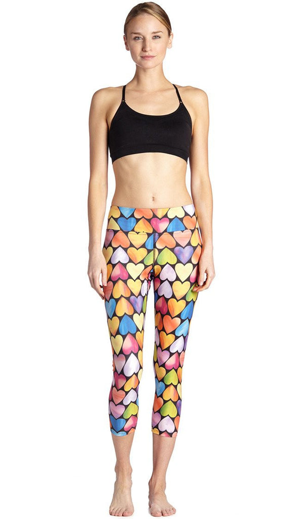 front view of model wearing colorful heart themed printed capri leggings